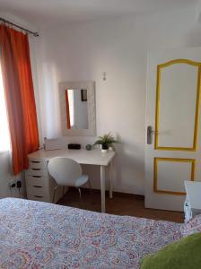 1 dormitorio con escritorio, espejo y cama en Clean and comfortable budget flat, en Fuengirola