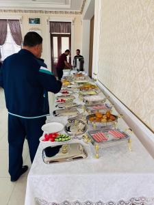 un hombre parado frente a una mesa de comida en MOUNTAIN VIEW SAMARKAND, en Samarkand