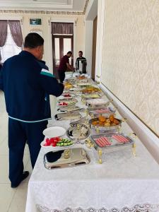 a man standing in front of a table of food at MOUNTAIN VIEW SAMARKAND in Samarkand