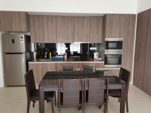 uma cozinha com uma mesa e cadeiras e um frigorífico em By The Sea Batu Ferringhi Beach Front Apartment Suite em Batu Ferringhi