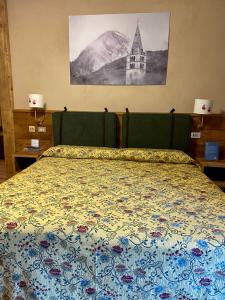 een slaapkamer met een bed met een quilt bij Hotel Chaberton in Cesana Torinese