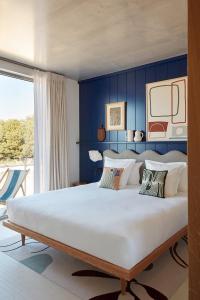 - une chambre avec un grand lit et un mur bleu dans l'établissement Hôtel de La Plage, à Biarritz