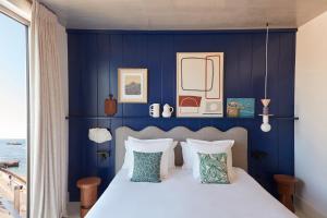 a bedroom with blue walls and a bed with pillows at Hôtel de La Plage in Biarritz