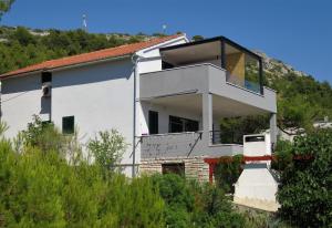 a white house with a balcony on a hill at Apartments Janči, Murter (Croatia) in Murter