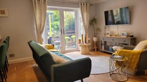 ロンドンにあるThree Bedroom Apartment by Beautiful Parkのリビングルーム(ソファ、椅子付)、ガラスのスライドドアが備わります。