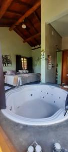 uma grande banheira num quarto com uma cama em Chalés e Bangalôs Capim Limão em Bueno Brandão