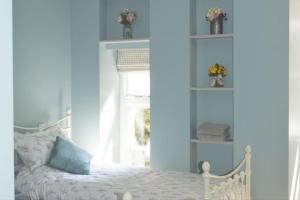 a bedroom with a white bed with blue walls at Victoria Lodge Woodhall Spa in Woodhall Spa