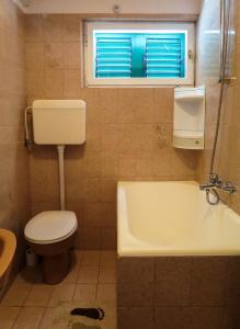 a bathroom with a toilet and a tub and a window at Apartments Janči, Murter (Croatia) in Murter