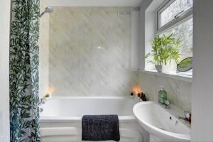 a bathroom with a bath tub and a sink at Cheerful 3 Bedroom Home, Sleeps 6 Guest Comfy, 1x Double Bed, 4x Single Beds, Free Parking, Free WiFi, Suitable For Business, Leisure Guest,Coventry, Midlands in Coventry