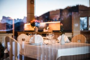 ラ・ヴァッレにあるHotel Ciurnadúの白いテーブルクロスとワイングラス付きのテーブル