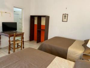 Ixtlán del Río的住宿－HOTEL MAYA IXTLAN，客房设有两张床和一张书桌及一台电视。