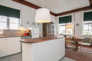 ボーゲンセにあるGuldbjerghus B&Bの白いキャビネットとテーブル付きのキッチンが備わります。