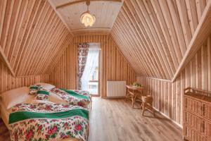 a bedroom with two beds in a room with wooden walls at GÓRALOWE domki & SPA in Bańska