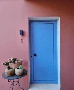 una puerta azul en una pared rosa con plantas en una mesa en Julietta Suites en Argostoli