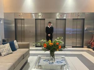 a man standing in a lobby with a vase of flowers at Bristol Condominio Apart Hotel in Mar del Plata