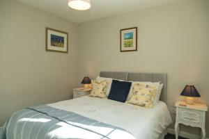 1 dormitorio con 1 cama con 2 mesitas de noche y 2 lámparas en Monks Cleeve Bungalow, en Exford