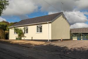 una casa bianca sul lato di una strada di Monks Cleeve Bungalow a Exford