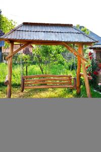 eine Holzbank mit einem Pavillon in einem Park in der Unterkunft Pensiunea Lucica in Vişeu de Jos