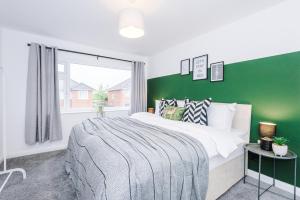 1 dormitorio con 1 cama grande y pared verde en Welcoming 3 bed home, 10 mins from Chester races and zoo, en Saughall