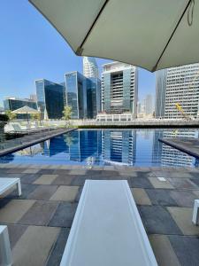 a white bench sitting next to a pool in a city at Wonderful Reva Aparthotel Downtown in Dubai