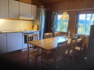 a kitchen and dining room with a wooden table and chairs at Stuga Huså Åre in Huså
