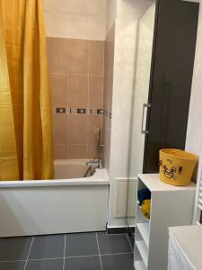 a bathroom with a tub and a shower with a yellow shower curtain at Welcome to Hakuna matata ! in Chanteloup-en-Brie