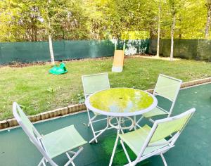 einen Tisch und vier Stühle in einem Hinterhof mit Pool in der Unterkunft Welcome to Hakuna matata ! in Chanteloup-en-Brie