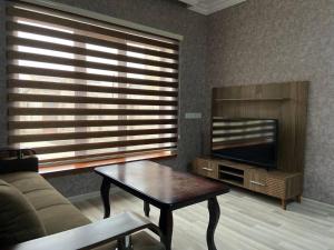 a living room with a couch and a table and a tv at Qusar House in Qusar