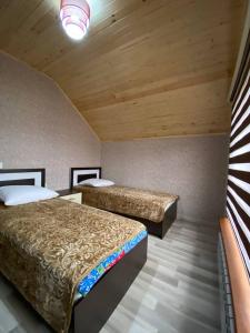 two beds in a room with wooden ceilings at Qusar House in Qusar