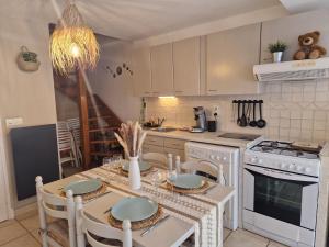 y cocina con mesa, sillas y fogones. en Maison de village à 35 m du bord de mer, en Marsella
