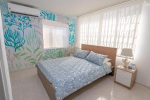 een slaapkamer met een bed met een blauw dekbed bij By The Sea Guest House in San Andrés