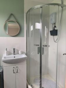 a bathroom with a shower and a sink and a mirror at Hugo's hideaway Free WIFI in Hemsby