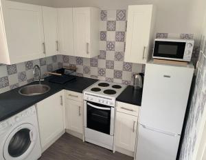 a small kitchen with a stove and a microwave at Hugo's hideaway, Belle Aire Free WIFI in Hemsby