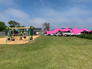 um parque com um parque infantil com guarda-sóis cor-de-rosa em Hugo's hideaway Free WIFI em Hemsby