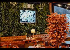 a restaurant with a plant wall with tables and a tree at Zlatna Nit in Novi Pazar