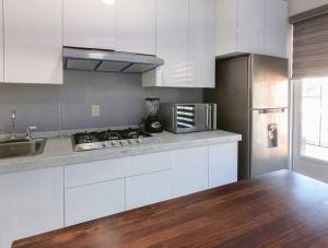 uma cozinha com armários brancos e um frigorífico de aço inoxidável em San Felipe Apartament em Uruapan