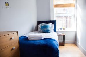 Un dormitorio con una cama azul y una ventana en City Centre 2 Bed Flat Sleeps 3 for Work and Leisure with Free Wifi by Amazing Spaces Relocations Ltd en Warrington