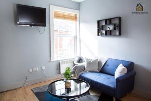 een woonkamer met een blauwe bank en een glazen tafel bij City Centre 2 Bed Flat Sleeps 3 for Work and Leisure with Free Wifi by Amazing Spaces Relocations Ltd in Warrington