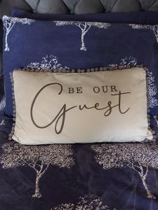 a bed with a pillow that reads be our guest at Lough View Lodge in Dunnamanagh