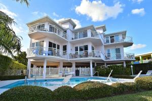 Casa blanca grande con piscina y sillas en Amadeus 6 en St Pete Beach