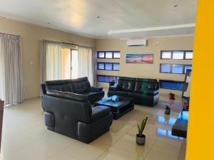 a living room with black leather couches and a table at Styled bed and breakfast in Palatswe