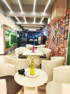 un restaurante con mesas y sillas blancas y una botella amarilla en Royal Galaxy, en Calcuta