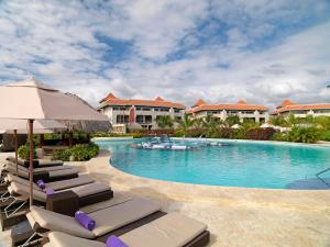 a swimming pool with lounge chairs and an umbrella at Garden Suites by Meliá - All inclusive in Punta Cana