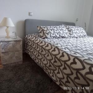 een bed met een zwart-wit dekbed en een bijzettafel bij Casa de huéspedes Villa de las Hortensias in Bustarviejo