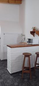 a kitchen counter with two stools and a microwave at Alojamiento El Coco in Puerto Madryn