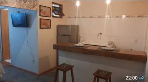 a kitchen with a counter with stools and a refrigerator at Kitnet 1 - Apart-Hotel Premium in Sete Lagoas