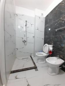 ein weißes Bad mit einer Dusche und einem WC in der Unterkunft Tomas Apartments Durres 1 in Durrës