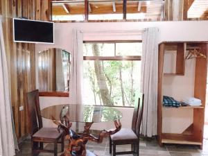 jadalnia ze szklanym stołem i krzesłami oraz oknem w obiekcie Casitas del Bosque Monteverde. w mieście Monteverde