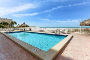 a swimming pool with chairs and the ocean in the background at Sea Breeze 401 in St Pete Beach