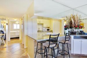 a kitchen with three bar stools and a counter at Sunset Chateau 506 - Premier in St Pete Beach